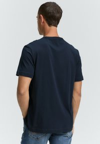 Camiseta de manga corta azul marino con cuello redondo, textura suave y dobladillo recto, combinada con jeans de mezclilla azul claro.