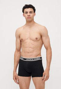 Fekete boxeralsó fehér rugalmas derékkal, amelyen a "JACK & JONES" felirat található. Az alsónadrág testhezálló kialakítású és pamutból készült.