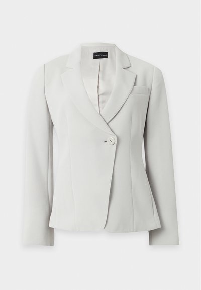 Blazer blanc cintré à manches longues, revers crantés, un bouton à l'avant et une poche poitrine, présenté sur fond uni.