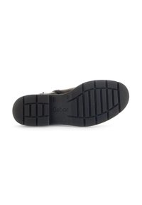 Suela de zapato sintético negra con un patrón de agarre texturizado. Presenta el logo "Gabor" y una correa para el tobillo ajustable para un ajuste seguro.