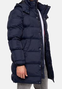 Marineblaue Steppjacke mit hohem Kragen, Druckknopf- und Reißverschlussverschluss, horizontalen Nähten und Fronttaschen. Glatte Textur, isoliertes Design.