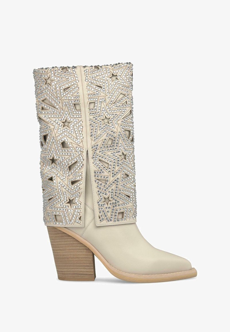 Beige Lederknöchelstiefel mit Stern-Ausschnitten und Strassverzierungen. Massiver Holzabsatz und spitz zulaufendes Design.