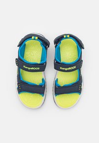 Marine sandaler med to justerbare borrelåsremmer, en lys cyan-fôr, og en teksturert gul innersåle med KangaROOS-logo.