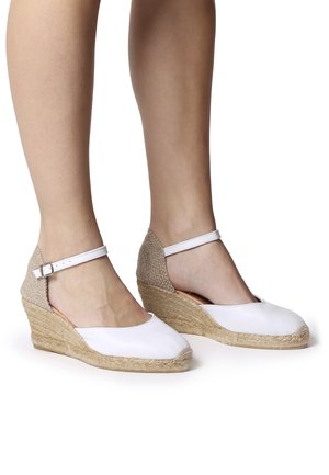 Espadrilles con zeppa in pelle bianca, con suola in corda di juta e retro beige strutturato, dotate di cinturino alla caviglia e punta arrotondata.