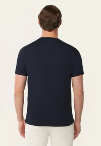 Marineblauwe t-shirt met korte mouwen en ronde hals, met een gladde textuur en een subtiele logo-detail nabij de kraag. Eenvoudig en getailleerd ontwerp.