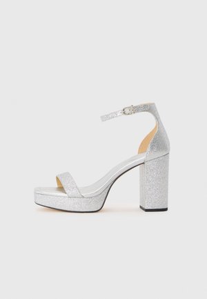 Silver glitter high-heeled sandal with a wide block heel, open toe, and adjustable ankle strap. Smooth interior and textured exterior.