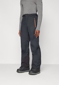Black waterproof ski pants with an orange zipper pocket, feature a straight cut and reinforced lower sections for durability and functionality.