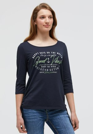 Marineblaues Langarm-T-Shirt mit Rundhalsausschnitt und 3/4-Ärmeln, versehen mit einem weißen und grünen Grafikdruck mit Text und einem Ankerdesign.