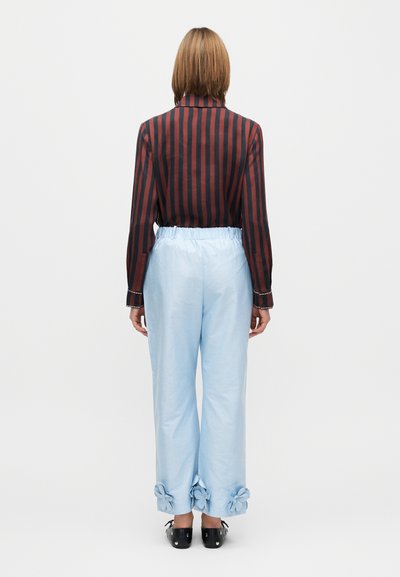 Cămașă cu dungi negre și roșii, pantaloni cu talie elastică albastre cu accente florale la tivuri. Material neted, croială lejeră, stil casual.