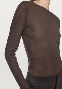 Long-sleeve top in dark brown, made of lightweight, slightly sheer fabric. Features a round neckline and fitted silhouette.