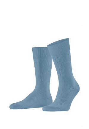 Paire de chaussettes montantes bleu clair texturées avec des bords côtelés, présentées debout sur fond blanc.