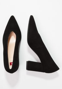 Scarpe donna con tacco a blocco in suede nero, una vista dall'alto e l'altra dal lato su uno sfondo bianco.