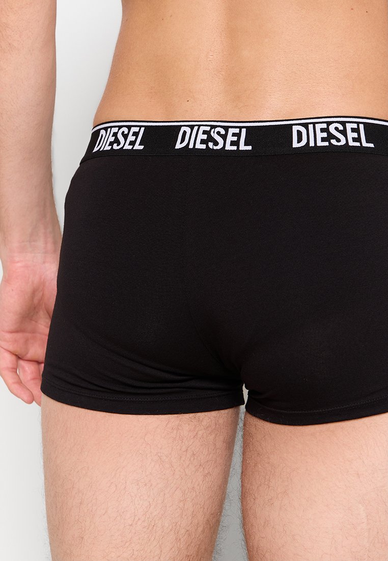 Schwarze Boxershorts mit eng anliegendem Schnitt, ausgestattet mit einem kontrastierenden weißen "DIESEL"-Logo auf dem elastischen Bund. Weicher, glatter Stoff.