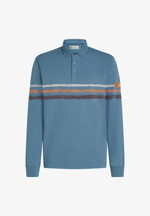 Plava dugorukava polo majica s tri gumba, bijele, narančaste i smeđe horizontalne pruge preko prsa, te okrugla kožna oznaka na lijevom rukavu.