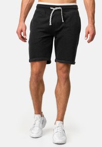Pantalones cortos de algodón gris oscuro con una cintura elástica y cordón ajustable, y dobladillos enrollados. Presentan una superficie texturizada y un cordón blanco en contraste.