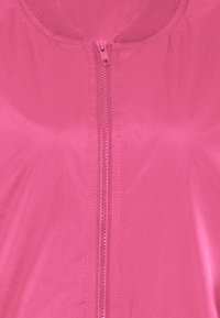 Roze zip-up jack gemaakt van soepel, lichtgewicht stof. Heeft een geribbelde kraag en een ritssluiting over de volle lengte, met een uniforme kleur gedurende het hele jack.