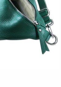 Groene, gestructureerde leren tas met een zilveren rits, zichtbare binnenvoering en een verstelbare strap bevestigd aan een metalen hardwarelus.