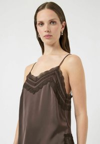 Brązowa satynowa koszulka na cienkich ramiączkach z delikatną koronką przy dekolcie i dole, regulowanymi cienkimi ramiączkami, miękką fakturą i luźnym krojem.