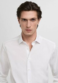 Witte overhemdd met klassieke kraag, slim fit. Glad weefsel, lange mouwen, subtiele glans en kleine knopen aan de voorkant.
