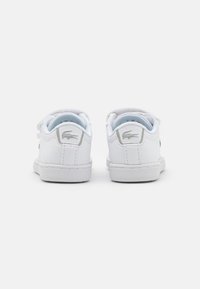 Zapatillas de cuero blanco con un diseño de corte bajo, punta redondeada, cierre de cordones en la parte delantera y un logotipo verde de Lacoste en el costado. Forro de textura suave.