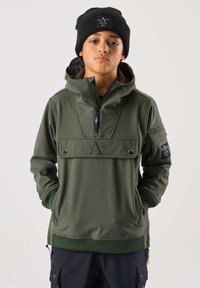 Grøn polstret hættetrøje med høj krave, halv lynlås og frontlomme. Har sorte logoaccenter og ribstrikkede manchetter. Bæres med en sort hue.