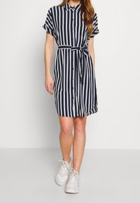Abito camicia blu navy a righe con maniche corte, chiusura con bottoni e cintura da annodare. Realizzato in tessuto leggero, presenta una vestibilità comoda.