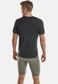 Short-sleeve, fitted black athletic shirt with a textured back and seamless design, paired with light green, diamond-patterned compression shorts.
