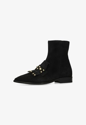 Black suede ankle boot with flat heel, pointed toe, and decorative strap featuring gold round studs across the front.