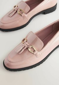 Roze lakirane loaferice s ravnim crnim potplatom, s zlatnim detaljima i resicama sprijeda.