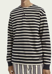 Langärmliges gestreiftes Hemd in Marineblau und Creme, mit Rundhalsausschnitt, drei Knöpfen am Kragen und gerippten Bündchen. Mit einem Etikett am Saum.