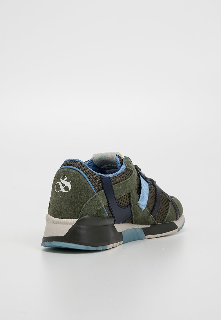 Trampki z zieloną zamszową cholewką, niebieskimi akcentami i czarnymi paskami. Charakteryzują się wyraźnym logo na pięcie oraz teksturowaną podeszwą.