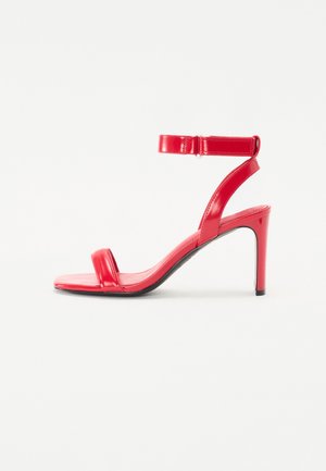 Red high-heeled sandal featuring a glossy patent leather finish, adjustable ankle strap, and two thin front straps. Lightweight and sleek design.