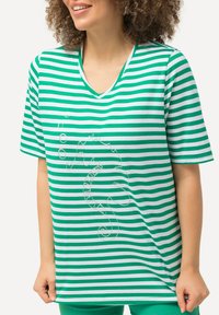 Zielono-biała pasiasta koszulka V-neck z krótkimi rękawami, z delikatnym nadrukiem konika morskiego z przodu. Miękki, casualowy materiał.