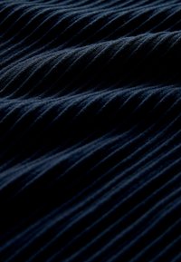 Granatowy, teksturowany materiał z pionowymi żebrami, prezentujący miękką powierzchnię i subtelny połysk, tworzący głębię dzięki różnym cieniom i fałdom.