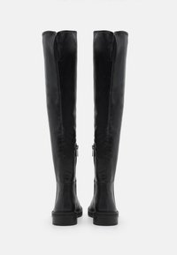 Botas de cuero negro por encima de la rodilla con un diseño elegante, que cuentan con una cremallera trasera y una suela de goma plana para mayor estabilidad.