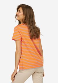 Camiseta de rayas con franjas horizontales en naranja y lavanda, de mangas cortas y escote redondo. La tela parece suave y casual.