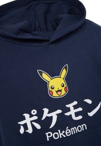 Navy Kapuzenpullover mit einem Pikachu-Graphic in Gelb mit schwarzen Akzenten, und dem Text "ポケモン" und "Pokémon" in Weiß unter dem Design.