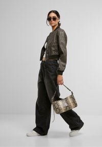 Must must võhik, valge särk, laiad mustad teksad, valged tossud ja käekott, millel on maoskinimuster ja kett.