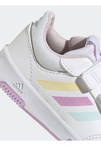 Białe sneakersy z teksturowaną skórzaną cholewką, z pastelowymi żółtymi, miętowymi i lawendowymi paskami. Różowa gumowa podeszwa i wyściełany kołnierz.