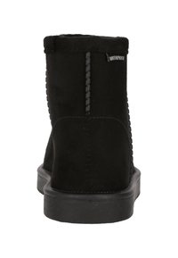 Botín negro impermeable hasta el tobillo con material de ante suave, puntera redonda, superficie texturizada y una suela de goma negra resistente. Presenta detalles de costura.