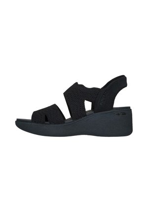 Sandalias de cuña negras con un upper de tejido texturizado, con tiras anchas y un diseño de punta abierta. Suela plana con un sutil detalle de estrías.