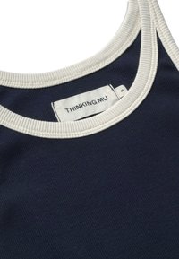 Débardeur en tissu côtelé bleu marine avec bordure côtelée blanche autour de l'encolure et des emmanchures, portant une étiquette blanche indiquant "THINKING MU" taille small.
