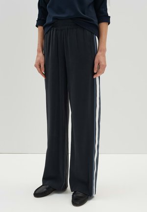 Pantalons noirs amples avec une taille élastique, présentant des rayures latérales verticales blanches et bleues. Tissu doux avec une texture lisse.