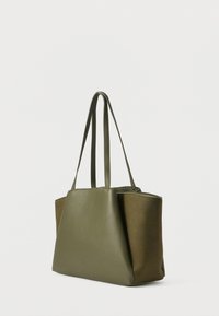 Olívazöld bevásárlótáska sima textúrával, téglalap alakú, két hosszú pánttal. Árnyalatblokkolt dizájnnal, sötétebb kiemeléssel.