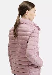 Puchowa kurtka w jasnym mauve, pikowana tekstura z poziomymi paskami, wysoki kołnierz i zamek błyskawiczny z przodu. Lekka, izolowana konstrukcja.