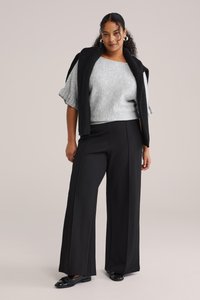 Harmaa neulottu villapaita, jossa on resorit hihansuissa, yhdistetty korkeavyötäröisiin mustiin leveälahkeisiin housuihin ja mustiin loafer-kenkiin, luoden rentoon asun.