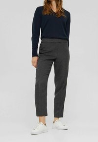 Pantalones de cuadros en blanco y negro con un corte ajustado, elaborados en una tela suave, combinados con zapatillas blancas y una camiseta de manga larga azul marino.