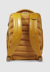 Mochila amarilla con textura acolchada, correas brillantes y herrajes metálicos. Presenta cierres de cremallera y un diseño ergonómico para mayor comodidad.