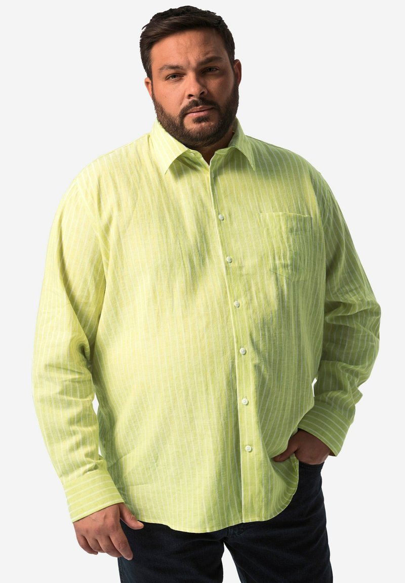 Camicia a maniche lunghe a righe verde chiaro in un tessuto morbido, con una chiusura a bottoni sul davanti e una tasca sul petto. Indossata con jeans scuri.