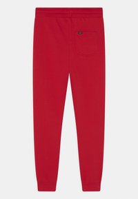 Czerwone bawełniane dresy z elastycznym pasem, prążkowanymi mankietami na kostkach i jedną kieszenią z tyłu z naszywką z logo.